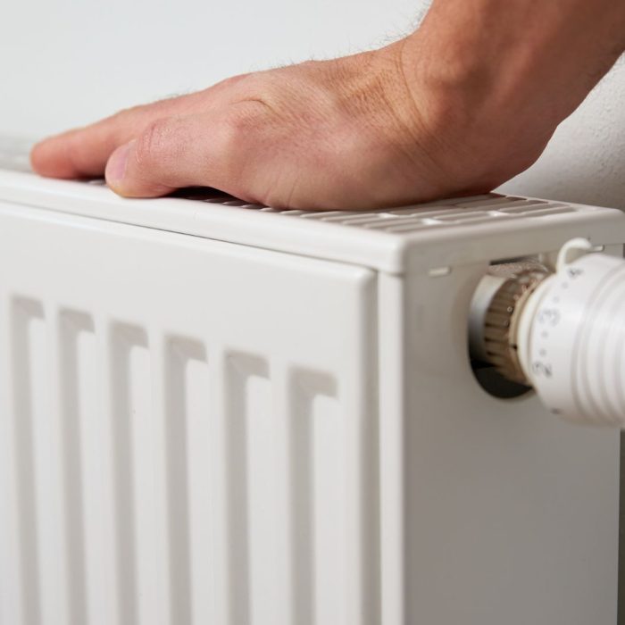 Mână de om care testează căldura unui calorifer.